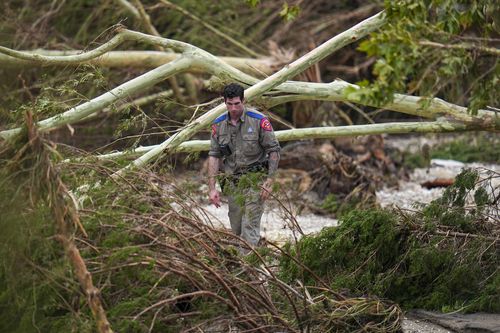 A Texas Department of Public Safety official combs through the banks of the Guadalupe River near Camp Mystic after a flash flood swept through the area Saturday, July 5, 2025, in Hunt, Texas. (AP Photo/Julio Cortez)