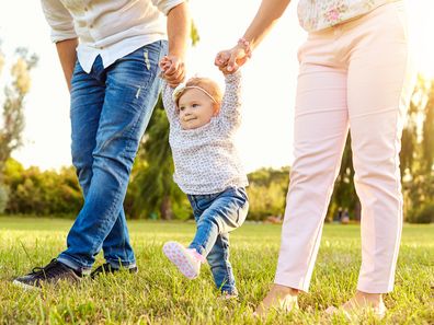 The first steps of the baby. Parents are teaching their child to walk. A happy family.