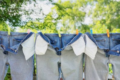 The washed jeans hang on a clothesline. Pockets turned inside out. Drying clothes on the street. 