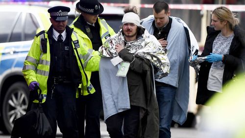 An injured man is aided by police outside Westminster Palace in central London. (Getty)