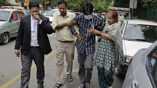 Puneet, second from right, is helped from a New Delhi court by his parents. (Image: AAP)

