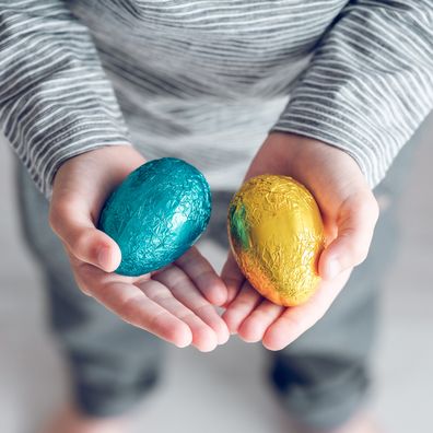 From above of unrecognizable kid showing eggs wrapped in foil prepared for Easter holiday