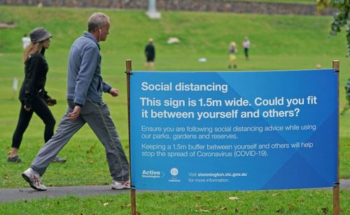 People exercise at a park which displays social distancing signage in Melbourne, Saturday, April 18, 2020.