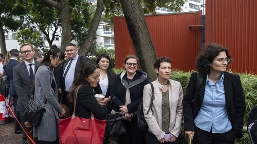 Representatives from various consulates wait in line outside the West Kowloon Magistrates' Courts in Hong Kong on Tuesday, Nov. 19, 2024, ahead of sentencing in the national security case. (AP Photo/Chan Long Hei)