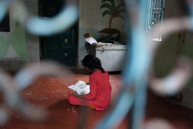 A girl who was rescued from child sex trafficking sits alone in a shelter.