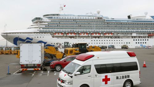 An ambulance leaves Yokohama Port where the Diamond Princess, back, is docked in Yokohama, near Tokyo, Friday, Feb. 14, 2020. The cruise ship is still carrying nearly 3,500 passengers and crew members under quarantine until at least Feb. 19. 