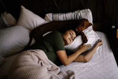 Woman and dog sleeping in same bed