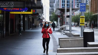 A woman wearing a face mask walks along George street in Sydney's CBD on April 8. Many people are working from home to help stop the spread of the coronavirus.