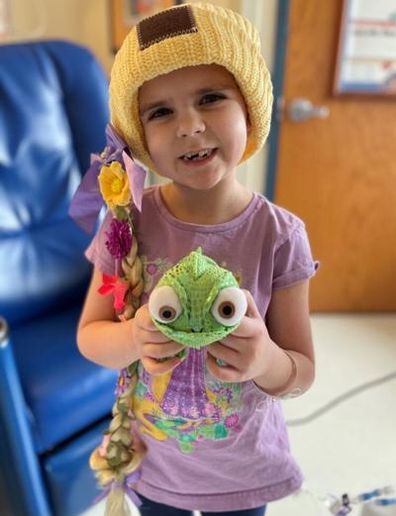 Young girl in hospital holding a toy frog.