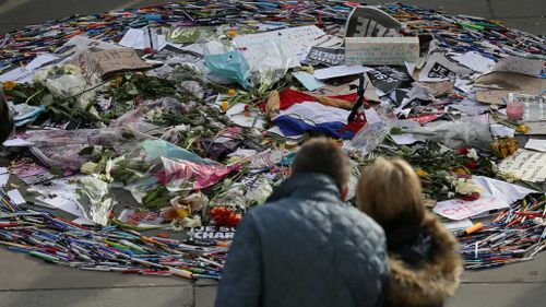 People look at a collection of pens and tributes during a memorial gathering for the victims of the recent terrorist attacks in France, in Trafalgar Square, London. (AAP)