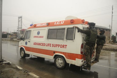 Soldiers hang on to an ambulance carrying bodies 