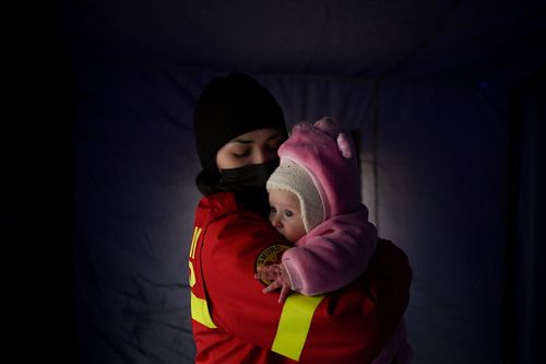 An employee from the Emergency Situation Inspectorate soothes the crying baby of a family fleeing the conflict from neighbouring Ukraine at the Romanian-Ukrainian border, in Siret, Romania, Saturday, Feb. 26, 2022. Romania, which shares around 600 kilometres (372 miles) of borders with Ukraine to the north, is seeing an influx of refugees from the country as many flee Russia's attacks. (AP Photo/Andreea Alexandru)