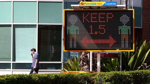 A man walks by COVID-19 safety signage outside Liverpool Hospital.