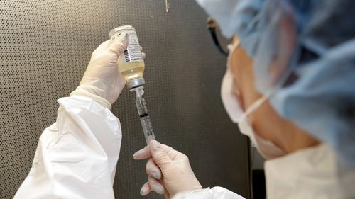 A pharmacy technician fills antibiotics into a syringe