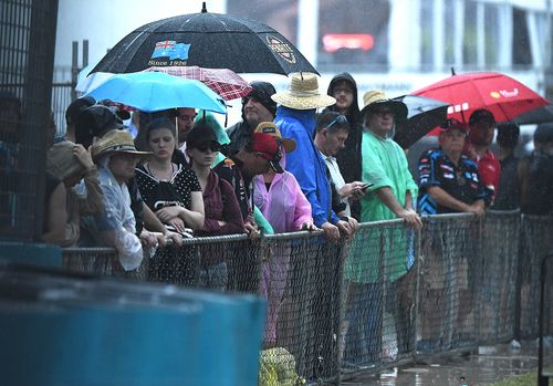 Fans at the GC600 Supercars event on Surfers Paradise are lashed by rain before the event is cancelled.